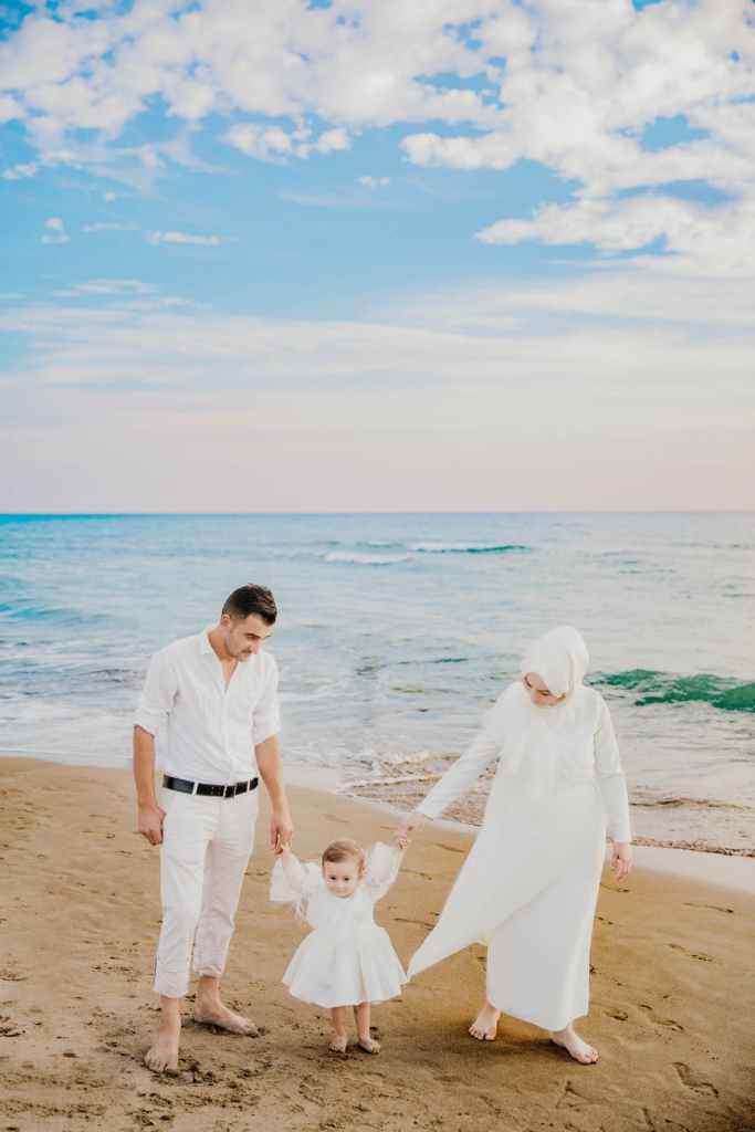 muslim family walking on sandy beach near sea in summer time